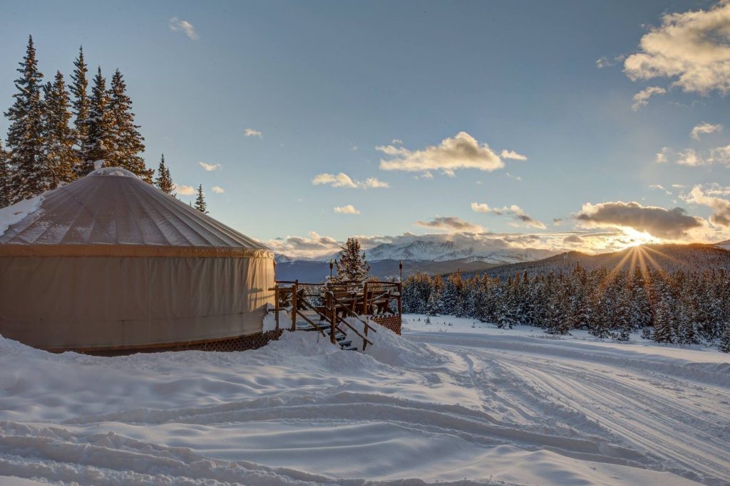 yurt in the snow with mountains in the background