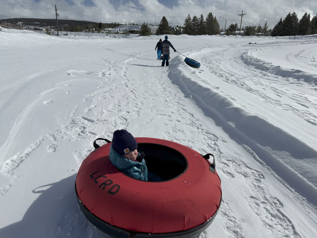Kids tubing down a snowy sledding hill in Leadville, Colorado