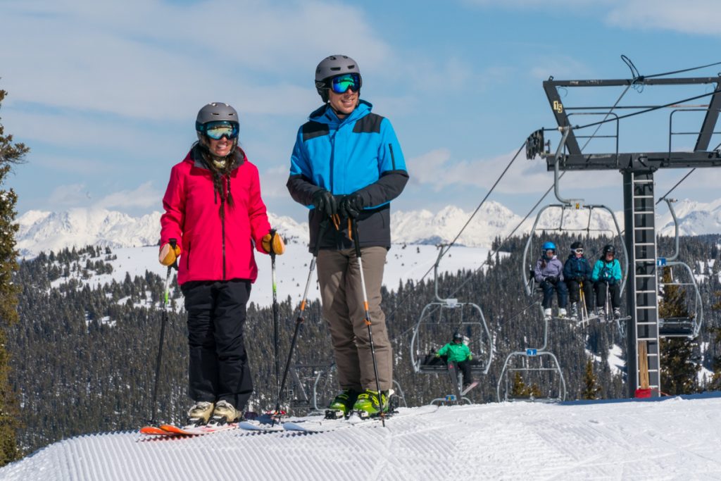 A smiling couple in colorful ski outfits on the slopes at Ski Cooper