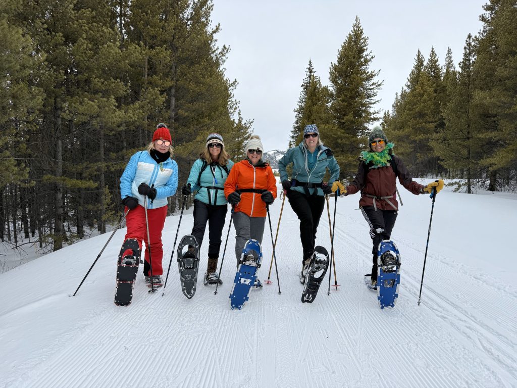 people posing for a photo in snow with snowshoes.