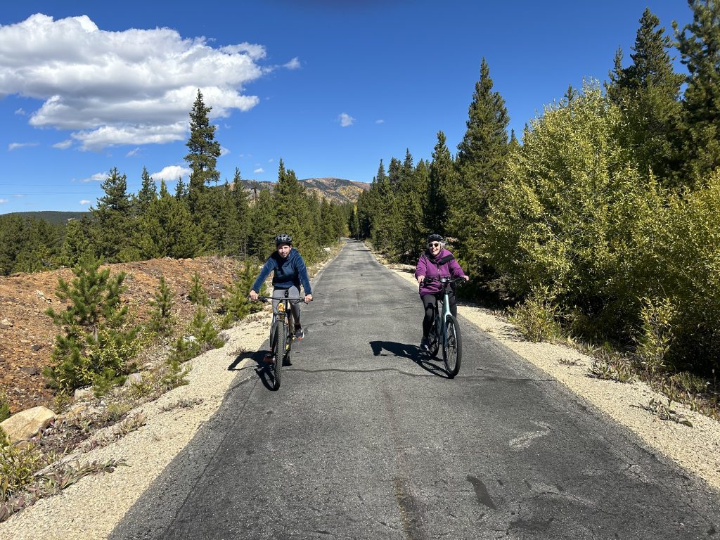 two people biking on a trail in the woods.