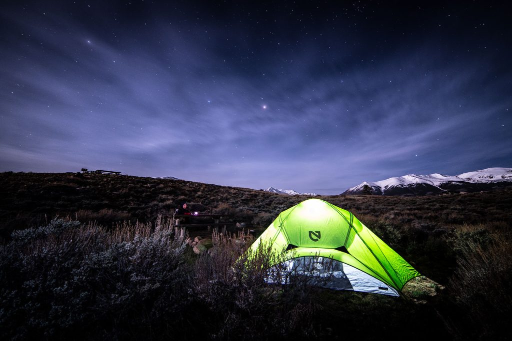 Tent lit from within at night under starry sky at Twin Lakes