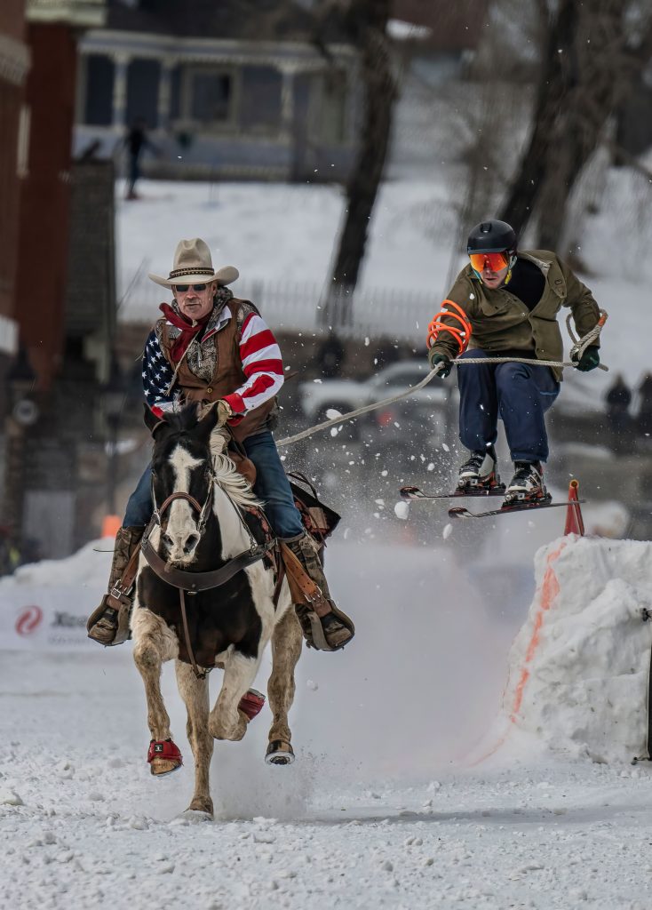 horse towing person on skis over s jump.