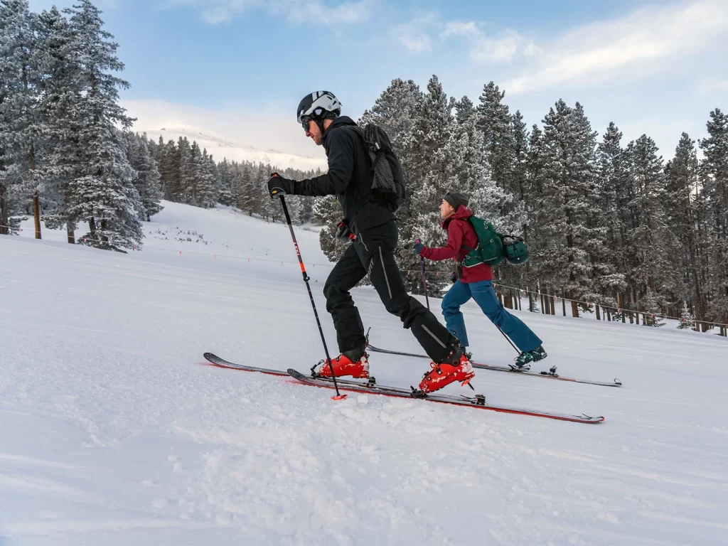 A backcountry skier skinning up a snowy slope in the Colorado Rockies
