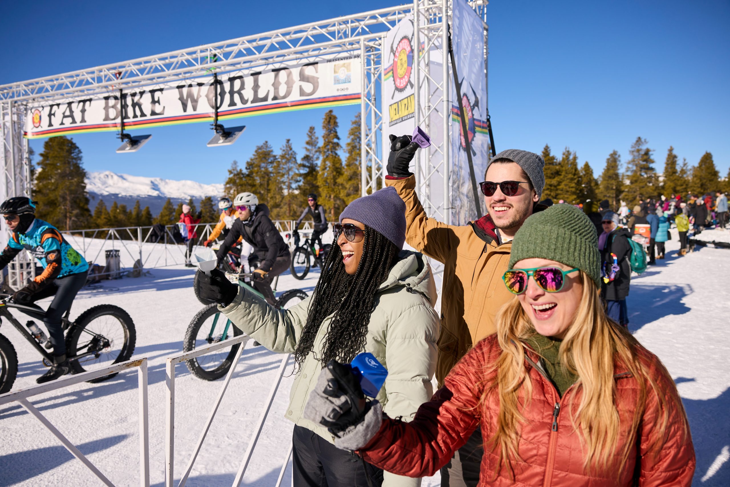 people standing by the start of a bike race in the snow.