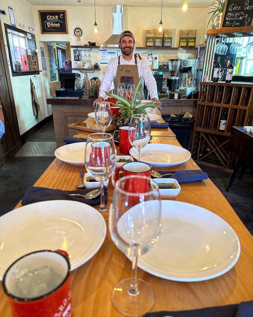 Chef Joe Mahoney of Elevated Culinary beside a table set for a family style dinner