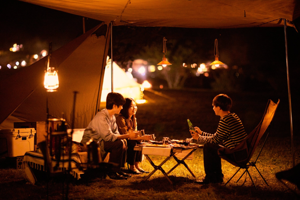 Group of campers gathered around a circle of lanterns at night